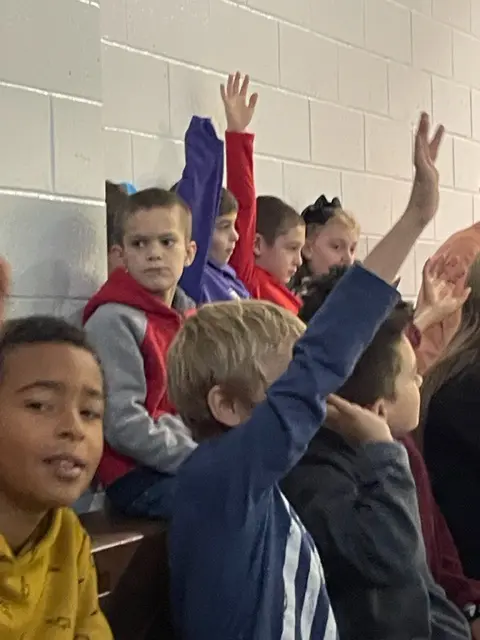 young kids raising hands in class