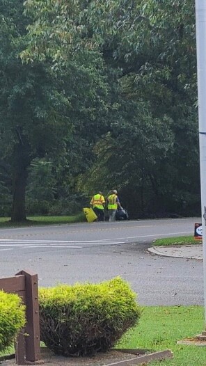 Two people doing road clean up in bright clothing